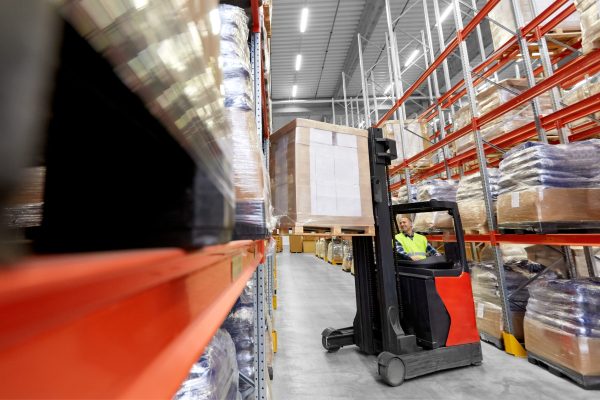 logistic business, shipment and loading concept - loader operating forklift with cargo at warehouse